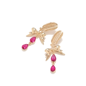 Detailed shot of golden feather earrings featuring pink pear-cut crystal pendants