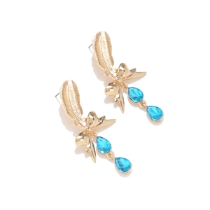 Detail of gold feather earrings with bowknot and dark blue teardrop crystals