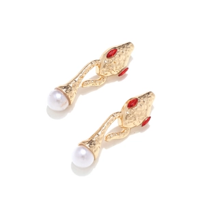 Detailed view of gold snake earrings with red gemstone eyes and white pearl pendants