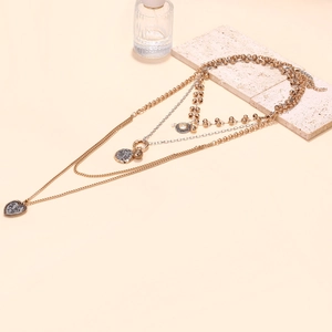 Detailed view of layered necklaces featuring heart and coin pendants on textured stone