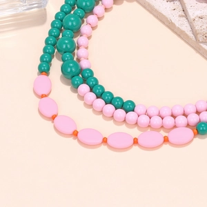 Detail of colorful multilayer beaded necklace with green and pink macaron-style beads