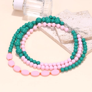 Detail of multi-layer beaded necklace with emerald and pink resin beads and metal chain