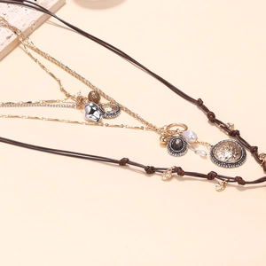 Close-up of layered bohemian necklace with coin, faux pearl, and heart pendants