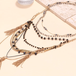 Multilayer beaded fringe necklace with gold chains and grey beads on stone background