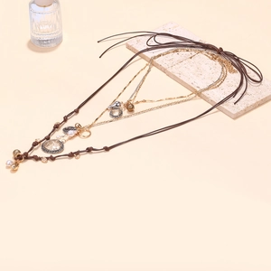 Detail of layered bohemian necklace with vintage coins, faux pearls, and woven wax cord