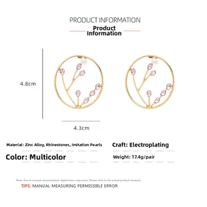 Detailed view of gold alloy hoop earrings with pink rhinestone flowers and pearl accents