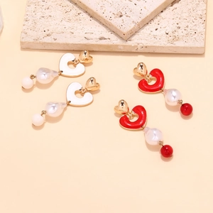Detailed view of Baroque pearl earrings with red and white enamel heart charms in gold
