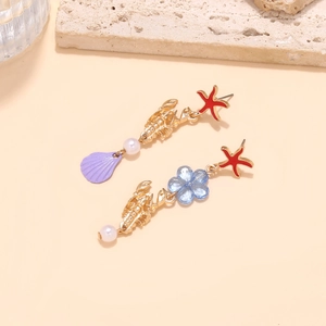 Detailed macro shot of creative sea life earrings featuring red starfish and golden lobster
