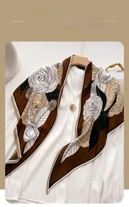 Close-up of herringbone camellia floral scarf draped over a white shirt on a wooden hanger