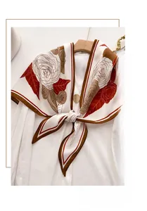 Detail of camellia floral print on a herringbone velvet silk scarf draped on a hanger