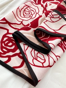 Dettaglio dello scialle in velluto con motivo a rose rosse e bordi neri rifiniti