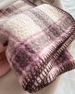 Gros plan d'une écharpe écossaise en tissu bouclé épais avec bordure brodée marron