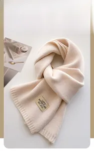 Gros plan détaillé de l'écharpe en maille beige crème avec étiquette de marque en tissu