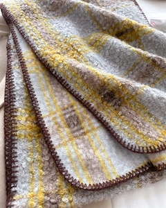 Détail d'écharpe à carreaux jaune et marron montrant la texture bouclée et couture