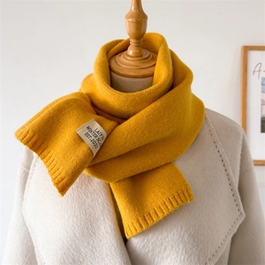 Détail de l'écharpe en tricot gingembre avec étiquette en tissu et bord côtelé