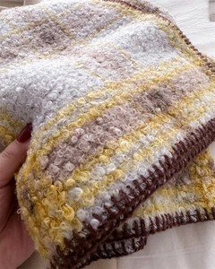 Détail d'une écharpe bouclée à carreaux jaunes et bruns montrant la texture épaisse