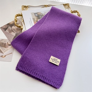 Détail de l'écharpe en maille violette avec étiquette de marque et finition côtelée