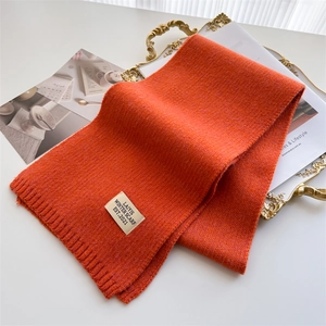 Détail de l'écharpe en maille orange avec étiquette tissée sur un tissu épais à côtes