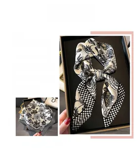 Vista macro di un foulard in seta bianco e nero con stampe di rose e bordi a scacchi