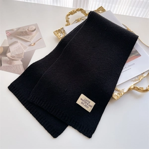 Détail de l'écharpe en maille noire avec texture vintage et étiquette en tissu de marque