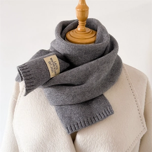 Détail d'une écharpe en maille grise avec bord côtelé et étiquette de marque vintage