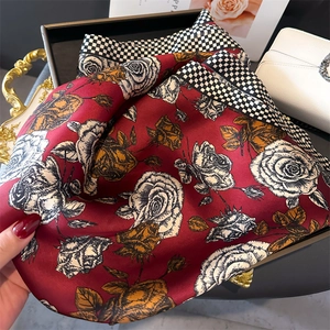 Dettaglio della sciarpa di seta rossa con stampa rose e bordo a scacchi con borsa