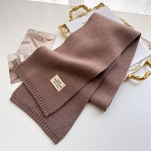 Gros plan sur l'écharpe en maille marron avec étiquette tissée vintage sur fond blanc