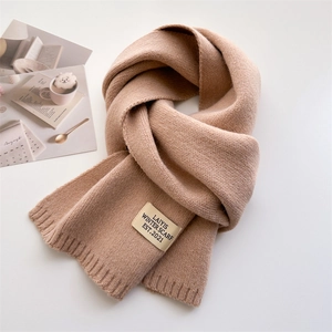 Gros plan sur la maille épaisse d'une écharpe beige avec étiquette de marque vintage