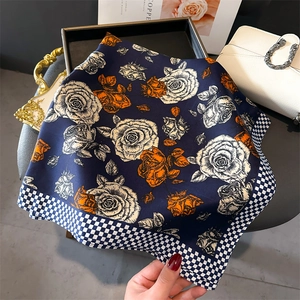 Dettaglio foulard in seta con bordo pied-de-poule e stampa floreale arancione vivace