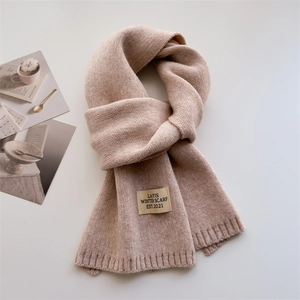 Détail d'une écharpe en maille beige avec bords côtelés et étiquette de marque vintage