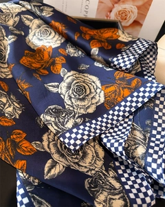Dettaglio di foulard in raso con rose arancioni e bordo a scacchi blu navy e bianco