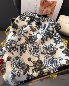 Dettaglio di foulard in seta con motivi a rose nere e bordi a scacchi su vassoio