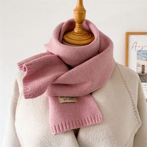 Détail de la maille et bord-côte d'une écharpe rose sur un manteau en laine blanc