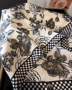 Dettaglio del foulard di seta con fiori e scacchi su un vassoio di presentazione