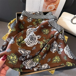Dettaglio di un lussuoso foulard in seta con rose caramello e bordi a scacchi neri