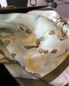 Detailed view of the mint green silk scarf featuring delicate white magnolia flower patterns