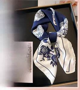 Detail of elegant silk scarf featuring navy blue rose print and smooth glossy texture