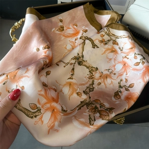 Close-up of lightweight satin scarf featuring elegant pink floral prints and silk texture