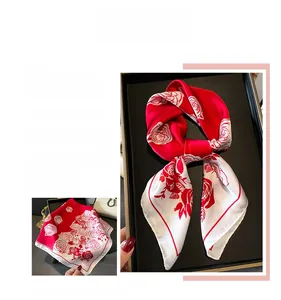 Detailed view of red rose print silk scarf folded in a gift box with flat layout display