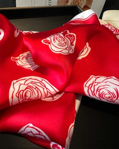 Detail of red silk scarf with white rose print displayed on a black decorative tray