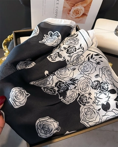 Close-up of elegant silk scarf with black and white rose floral print and white piping