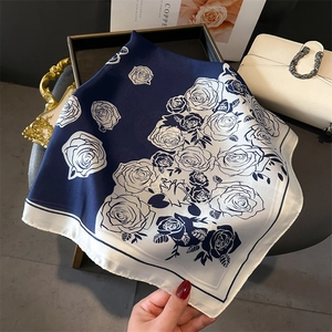 Detail of navy blue rose print silk-like scarf draped elegantly on a designer bag