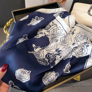 Detailed view of rose print silk scarf with navy blue and white floral contrast