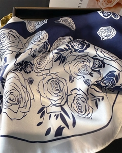Close-up of rose floral print silk scarf with navy blue and white contrast in a gift box