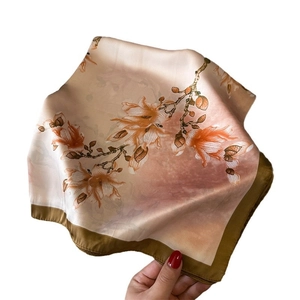 Champagne floral silk scarf with magnolia print and brown border held by hand