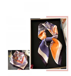 Détail d'un foulard satiné avec motifs équestres de chevaux et détails de chaînes