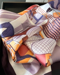 Détail d'un foulard en soie avec motifs de chevaux et rayures dans un coffret cadeau