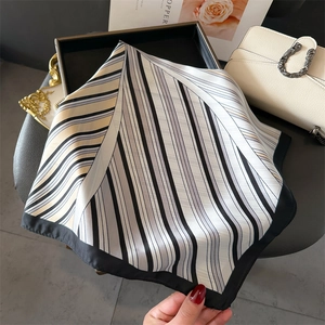 Détail du foulard en soie à rayures avec bordure noire élégante sur un plateau chic