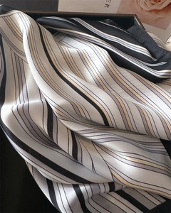 Gros plan d'un foulard carré à rayures en soie synthétique dans un coffret cadeau