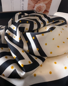 Détail d'un foulard en soie aux motifs zigzag noir et blanc et pois jaunes